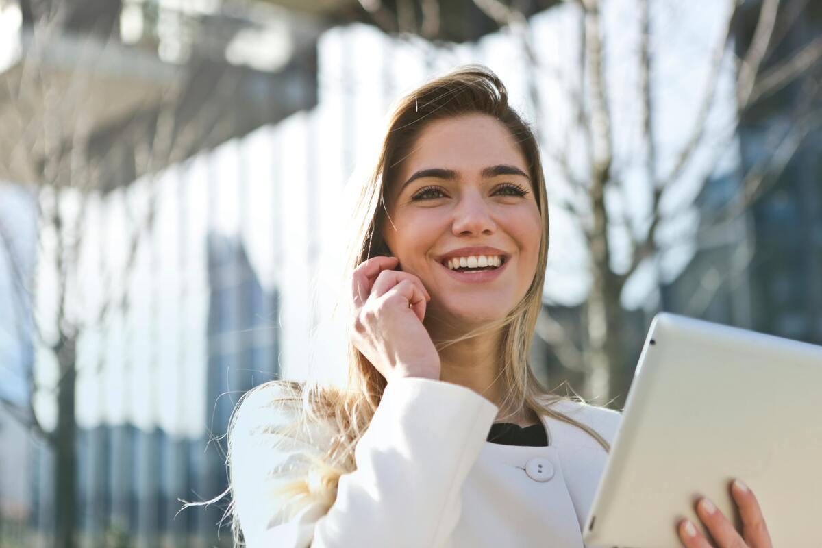 woman on a mobile in a white blazer holding tablet, share capital advantages and disadvantages